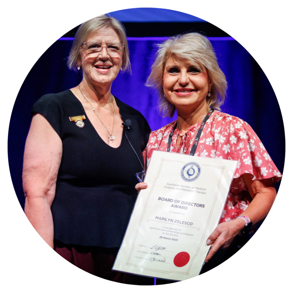 Marilyn Zelesco smiling, holding her Board Award certificate.