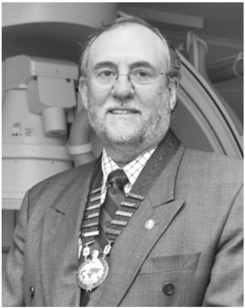 Robert George wearing a medallion and smiling.